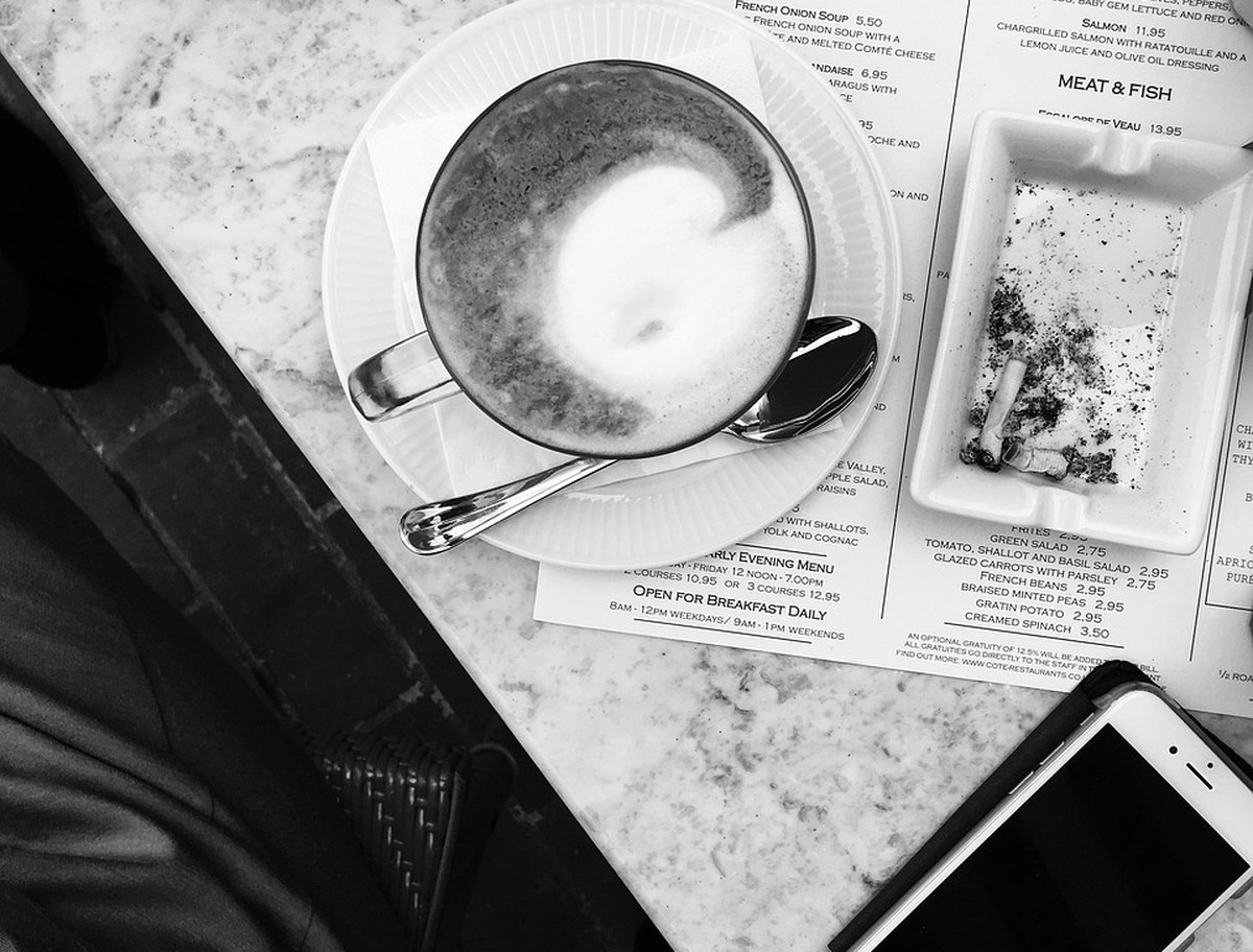 Smartphone und Kaffee auf einem hellen Marmortisch neben einer Zeitschrift